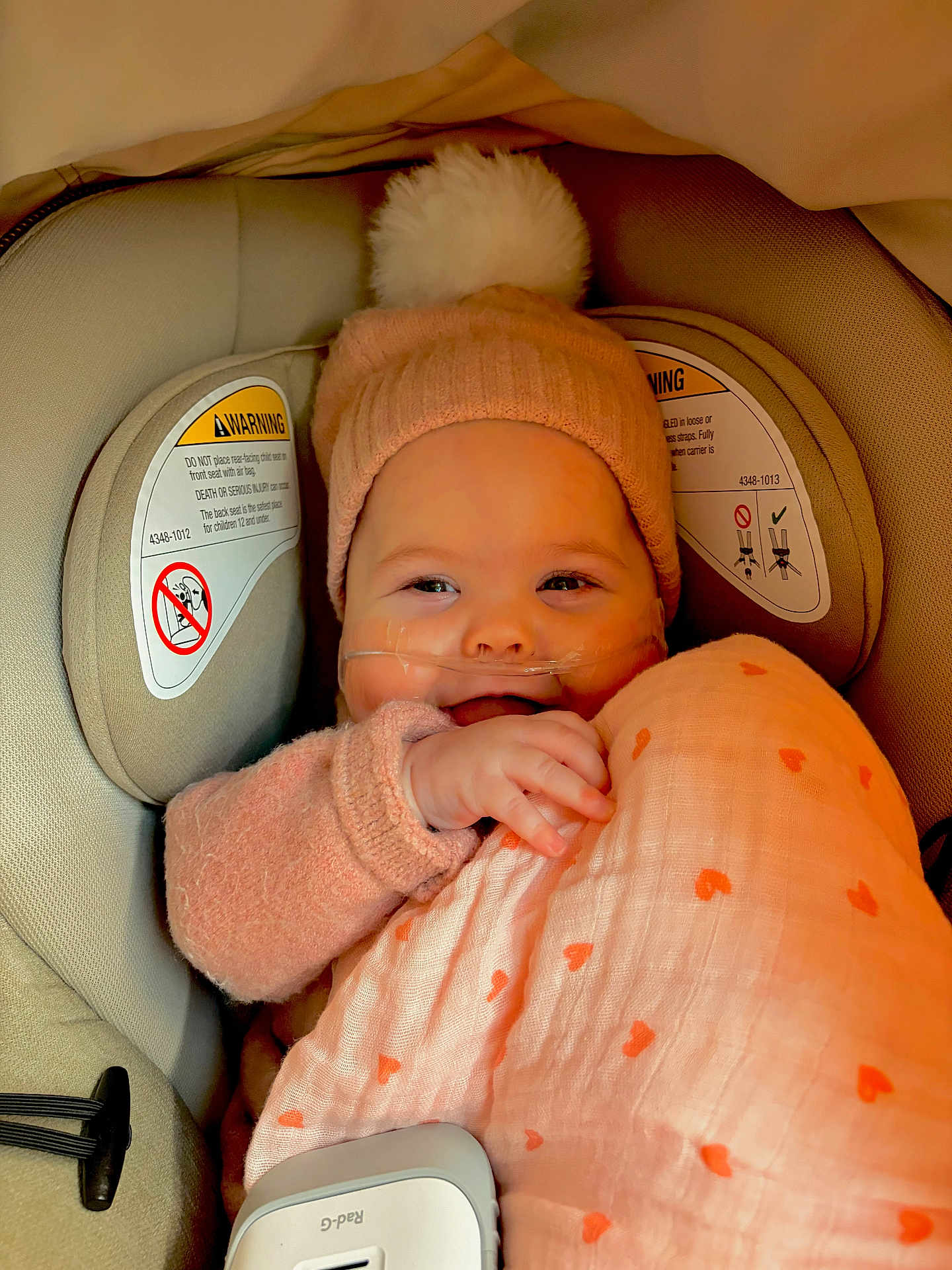 Angelina Terracciano is registered to the contest to win money with this photo: baby, beanie, blanket, candid, car_seat, child, close_up, cozy, fabric, hand, heart_pattern, infant, nasal_cannula, oxygen_tubing, pink, pompom, portrait, seat_padding, smile, warning_label
