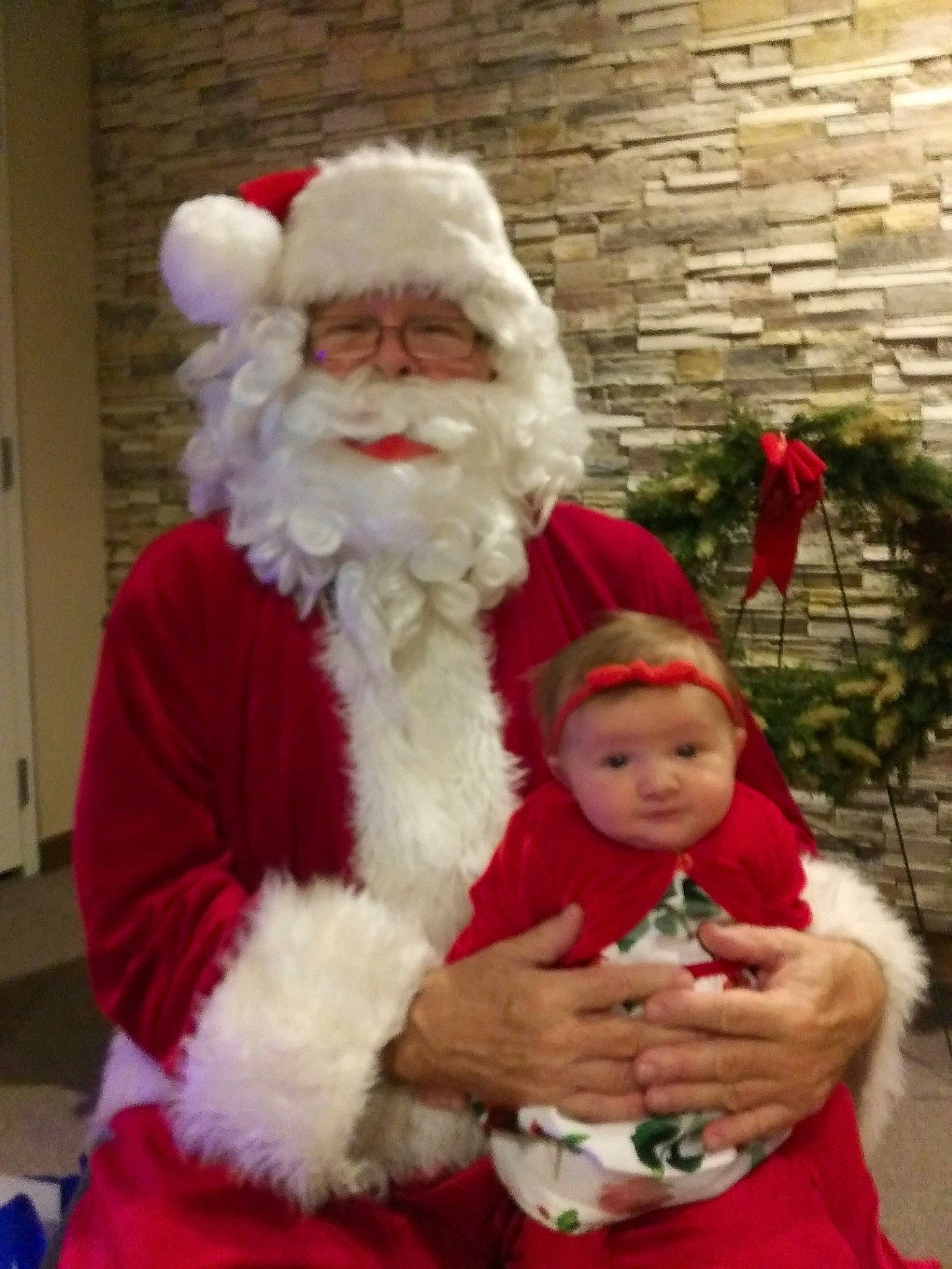 Joy is registered to the contest to win money with this photo: arm, beard, christmas, christmas_eve, costume_accessory, event, facial_hair, fictional_character, fur_clothing, hand, hat, headwear, holiday, human, human_body, lap, mammal, moustache, nose, person