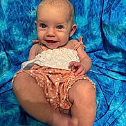 Abigail is registered to the contest to win money with this photo: baby, smiling, child, portrait, blue_background, sitting, cute, happy, infant, clothing, fabric, skin, foot, hand, eyes, head, person, playful, cheerful, photography