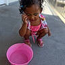 Aviora joined the competition — help win amazing prizes! toddler, child, pink_bucket, hair_ties, curly_hair, makeup, squatting, outdoor, concrete_floor, shoes, colorful_clothing, summer, play, expression, person, small_bucket, casual, daylight, curiosity, fun