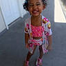 child, colorful_clothing, concrete_floor, curly_hair, cute, daylight, donut_pattern, fashion, fun, girl, happy, outdoor, pigtails, playful, portrait, sandals, smiling, standing, summer, young_child