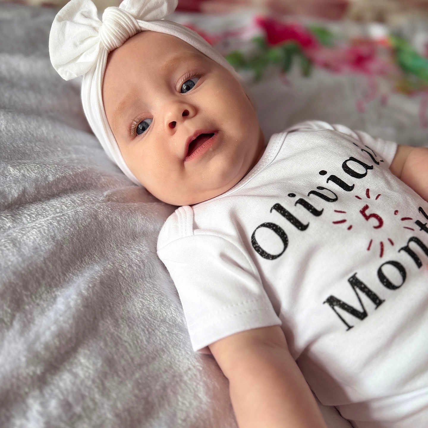 Olivia joined the competition — help win amazing prizes! baby, bed, blanket, bow, child, closeup, clothing, cute, expression, face, headband, indoors, infant, lying_down, onesie, person, portrait, skin, soft, young