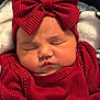 baby, sleeping, red_clothing, headband, bow, infant, cute, face, closed_eyes, soft_texture, warm, child, portrait, cozy, newborn, adorable, knitwear, resting, indoors, blanket