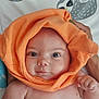 baby, infant, orange_cloth, face, eyes, hand, skin, expression, cute, adorable, hood, fabric, texture, sloth_illustration, background, bed, person, portrait, newborn, child