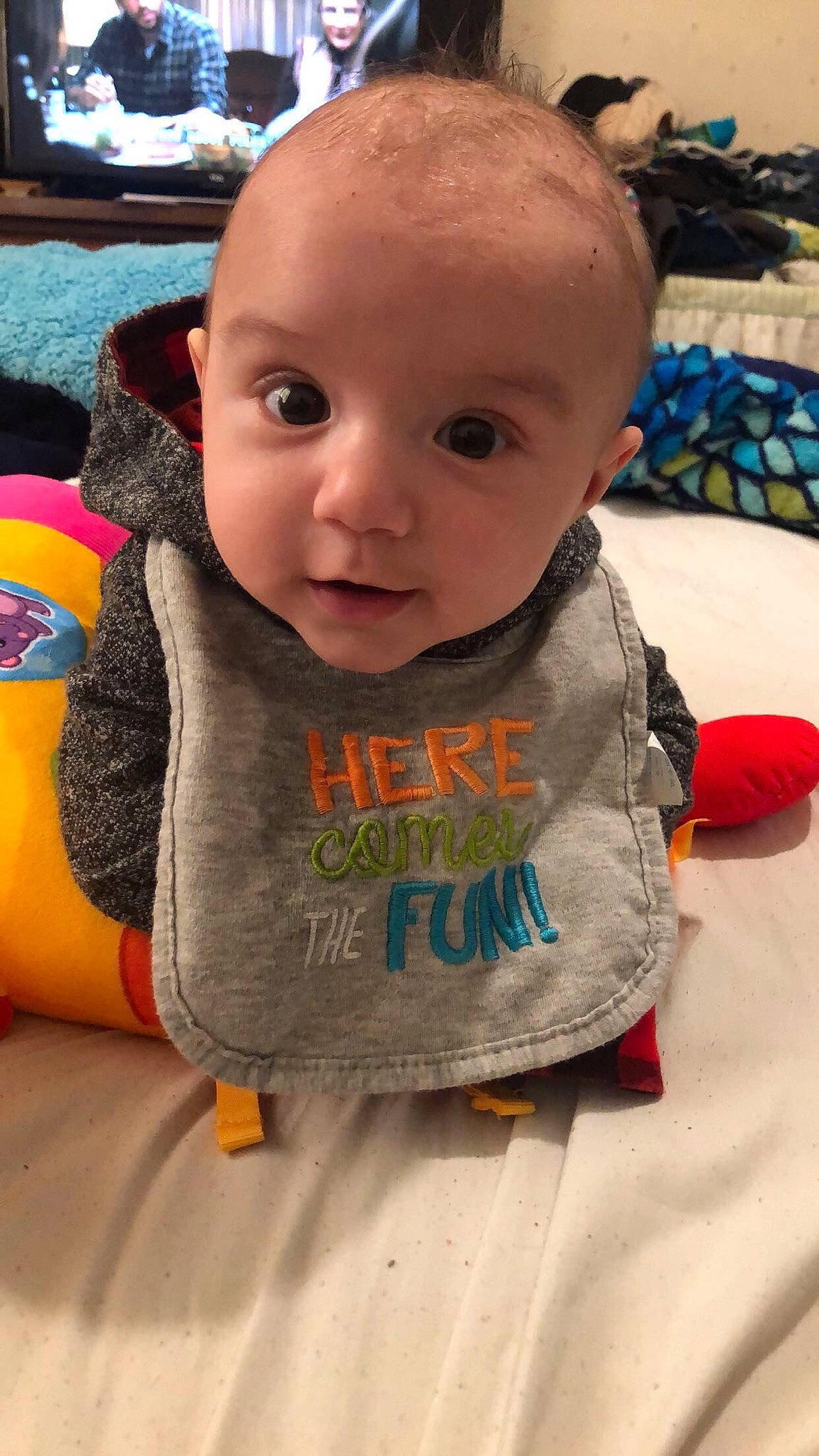 Kaleb is registered to the contest to win money with this photo: baby, baby_toddler_clothing, bib, blurred, cheek, child, chin, flooring, fun, happy, head, human_body, iris, leisure, mouth, nose, orange, person, skin, sleeve