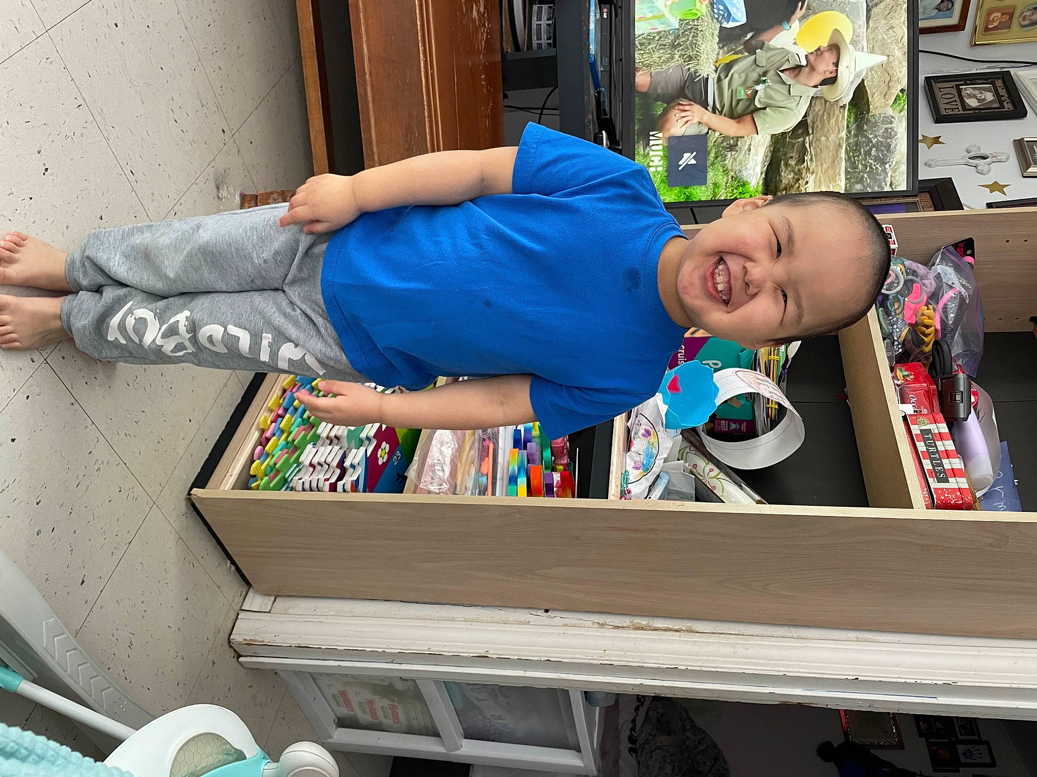 Desmond is registered to the contest to win money with this photo: arm, box, cart, child, electric_blue, fun, human, human_leg, joy, leisure, person, room, sitting, smile, standing, street, t_shirt, textile, toddler, transport