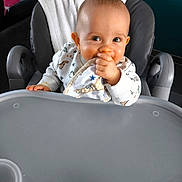 Elyo a rejoint le concours — aidez-le/la à gagner de superbes lots ! baby, high_chair, cloth, chewing, cushion, face, person, indoor, smile, curious, hand, furniture, pacifier, white_towel, sweater, dinosaur_pattern, head, skin, table, seat