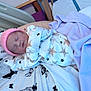 newborn, baby, sleeping, pajamas, pink_hat, star_pattern, blanket, butterfly_print, bed, adult_arm, resting, indoors, cozy, soft_lighting, child, infant, cute, peaceful, clothing, portrait