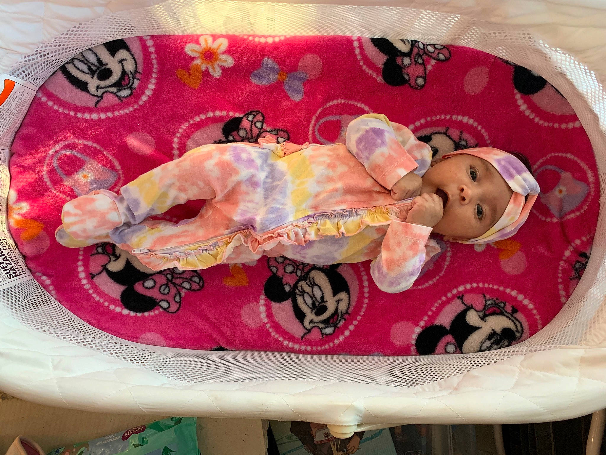 Emelia is registered to the contest to win money with this photo: arm, baby, baby_products, baby_toddler_clothing, bed, child, circle, comfort, doll, fashion_accessory, headgear, headwear, linens, magenta, pattern, peach, person, pink, sleeve, textile