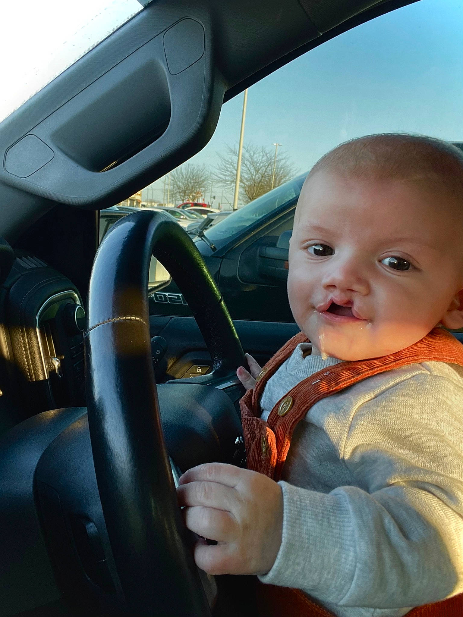 Phillip is registered to the contest to win money with this photo: automotive_design, automotive_exterior, automotive_mirror, baby_toddler_clothing, car, finger, gesture, hand, head, mode_of_transport, motor_vehicle, person, personal_luxury_car, rear_view_mirror, sky, steering_part, steering_wheel, toddler, vehicle, vehicle_door