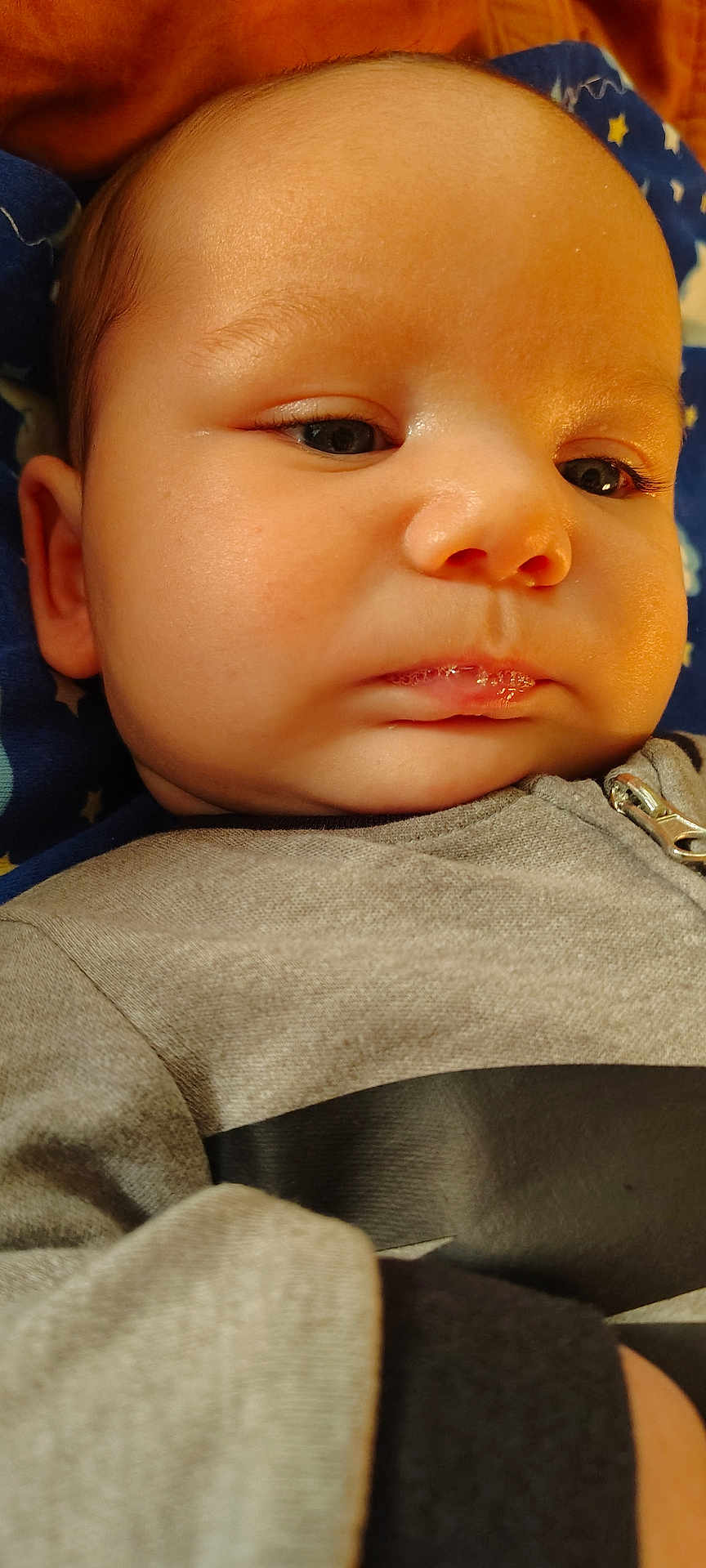Tobias joined the competition — help win amazing prizes! baby, close_up, face, infant, child, clothing, grey_outfit, zipper, blanket, blue_blanket, stars, skin, head, expression, serious, portrait, indoors, young_child, cute, person