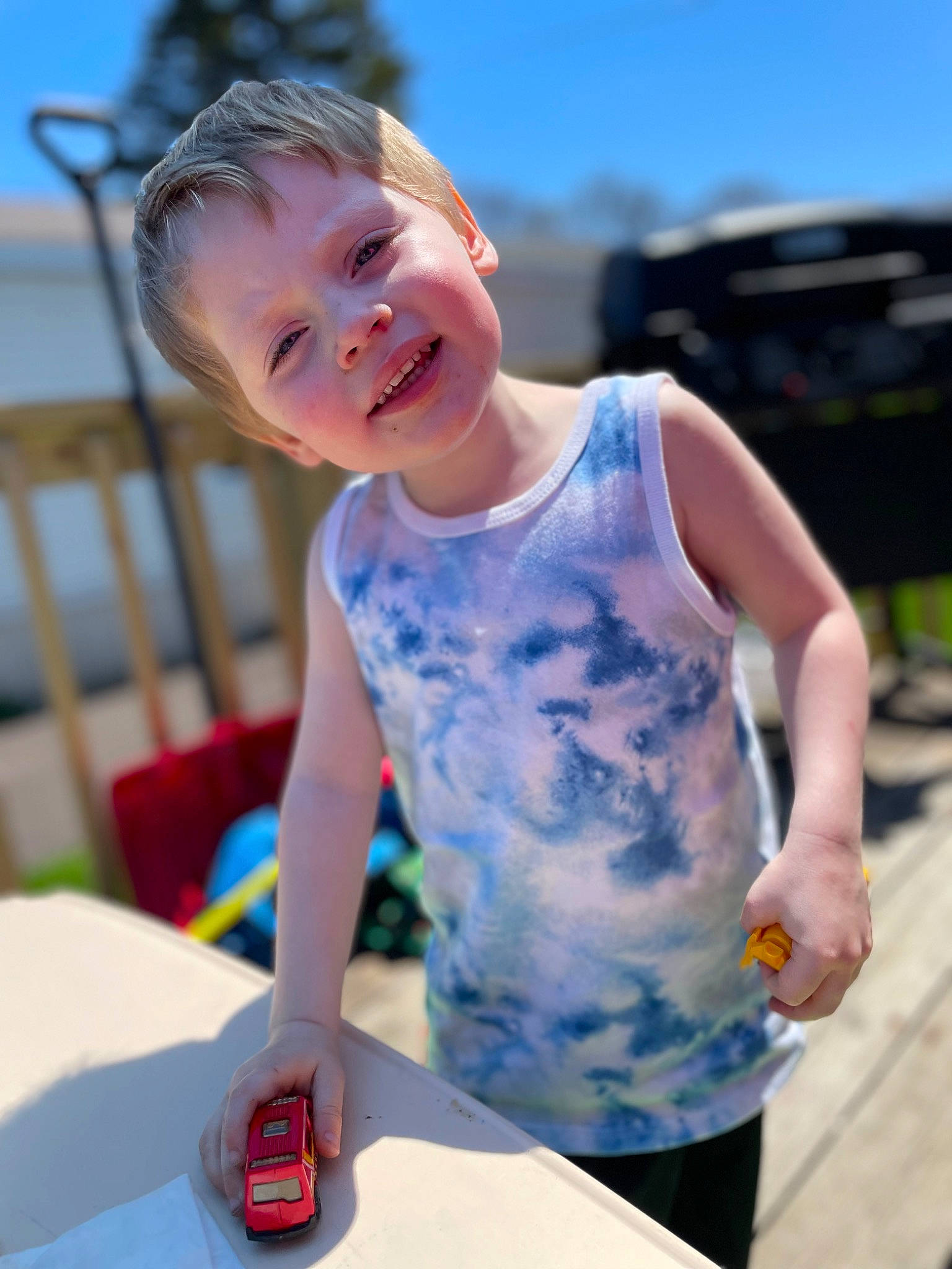 Kayden is registered to the contest to win money with this photo: baby, child, electric_blue, facial_expression, fun, hairstyle, happy, joy, leisure, mobile_phone, person, play, recreation, red, shorts, sitting, sky, smile, t_shirt, table
