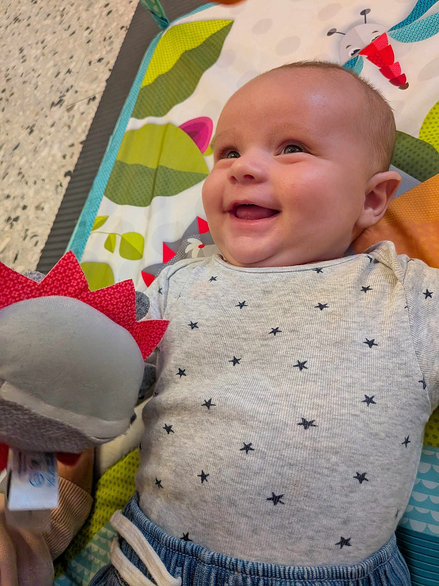 Bastien a rejoint le concours — aidez-le/la à gagner de superbes lots ! baby, smiling, plush_toy, play_mat, infant, clothing, stars_pattern, happy, cute, child, indoor, person, closeup, face, head, joy, colorful, soft_toy, baby_girl, baby_boy