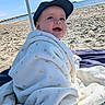Bastien a rejoint le concours — aidez-le/la à gagner de superbes lots ! baby, beach, blanket, cap, child, cozy, cute, daytime, happy, headwear, outdoor, playful, portrait, relaxation, sand, sea, smile, sunny, towel, umbrella