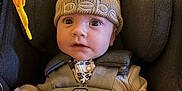 Marley joined the competition — help win amazing prizes! baby, car_seat, hat, pom_pom, knitwear, infant, straps, clothing, toy, curious, wide_eyes, child, seatbelt, cute, indoors, portrait, face, small_hands, warm, cozy