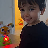 Liam participe au concours pour gagner de l'argent avec cette photo : background, black_shirt, child, curtain, cute, expression, face, furniture, glowing, hair, home, indoor, light, person, plaything, room, smile, table, toy, young