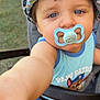 toddler, child, pacifier, hat, dinosaur_pattern, blue_eyes, paw_patrol, shirt, stroller, outdoor, grass, baby, arm, face, cute, summer, sunlight, portrait, infant, baby_clothing