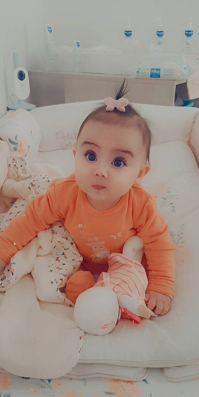 Giuliana participe au concours pour gagner de l'argent avec cette photo : baby, baby_products, baby_sleeping, baby_toddler_clothing, cheek, child, comfort, flooring, foot, happy, human_leg, knee, linens, person, pink, room, sitting, skin, sleeve, surprise