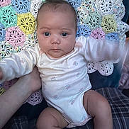 Leah is registered to the contest to win money with this photo: baby, infant, onesie, crocheted_blanket, pastel_colors, handmade, pattern, child, cute, face, skin, person, holding_hand, sitting, indoors, plush, soft, young_child, comfort, portrait