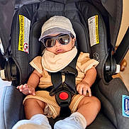 Nathanael is registered to the contest to win money with this photo: baby, car_seat, sunglasses, hat, knitted_clothing, white_sneakers, infant, seat_belt, safety_harness, child, casual_clothing, indoor, cute, fashion, portrait, relaxed, accessory, comfort, modern, adorable