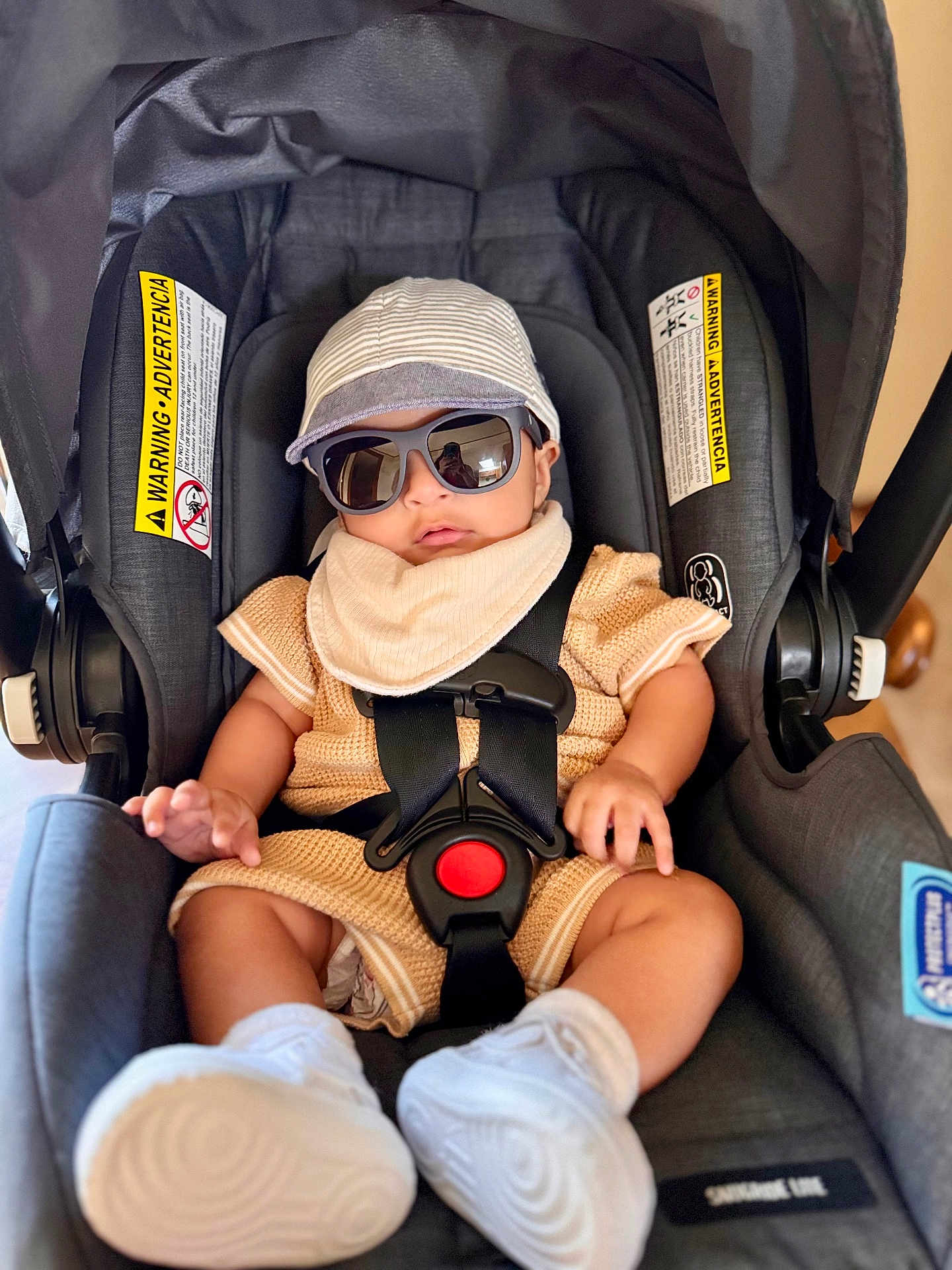 Nathanael is registered to the contest to win money with this photo: baby, car_seat, sunglasses, hat, knitted_clothing, white_sneakers, infant, seat_belt, safety_harness, child, casual_clothing, indoor, cute, fashion, portrait, relaxed, accessory, comfort, modern, adorable