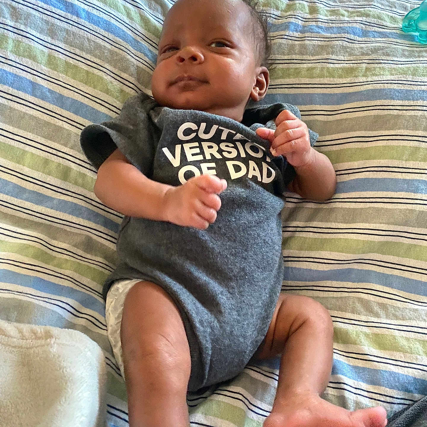 Semaj joined the competition — help win amazing prizes! baby, bed, blanket, child, clothing, cute, expression, fist, foot, hand, indoor, infant, lying_down, newborn, onesie, person, portrait, skin, smile, striped_bedspread