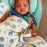 baby, blanket, blue, cushion, infant, pacifier, pattern, person, portrait, shirt, sleeping_bag, soft_toy, toddler, toy, wearing, wrapped, young_child, indoors, comfort, seated
