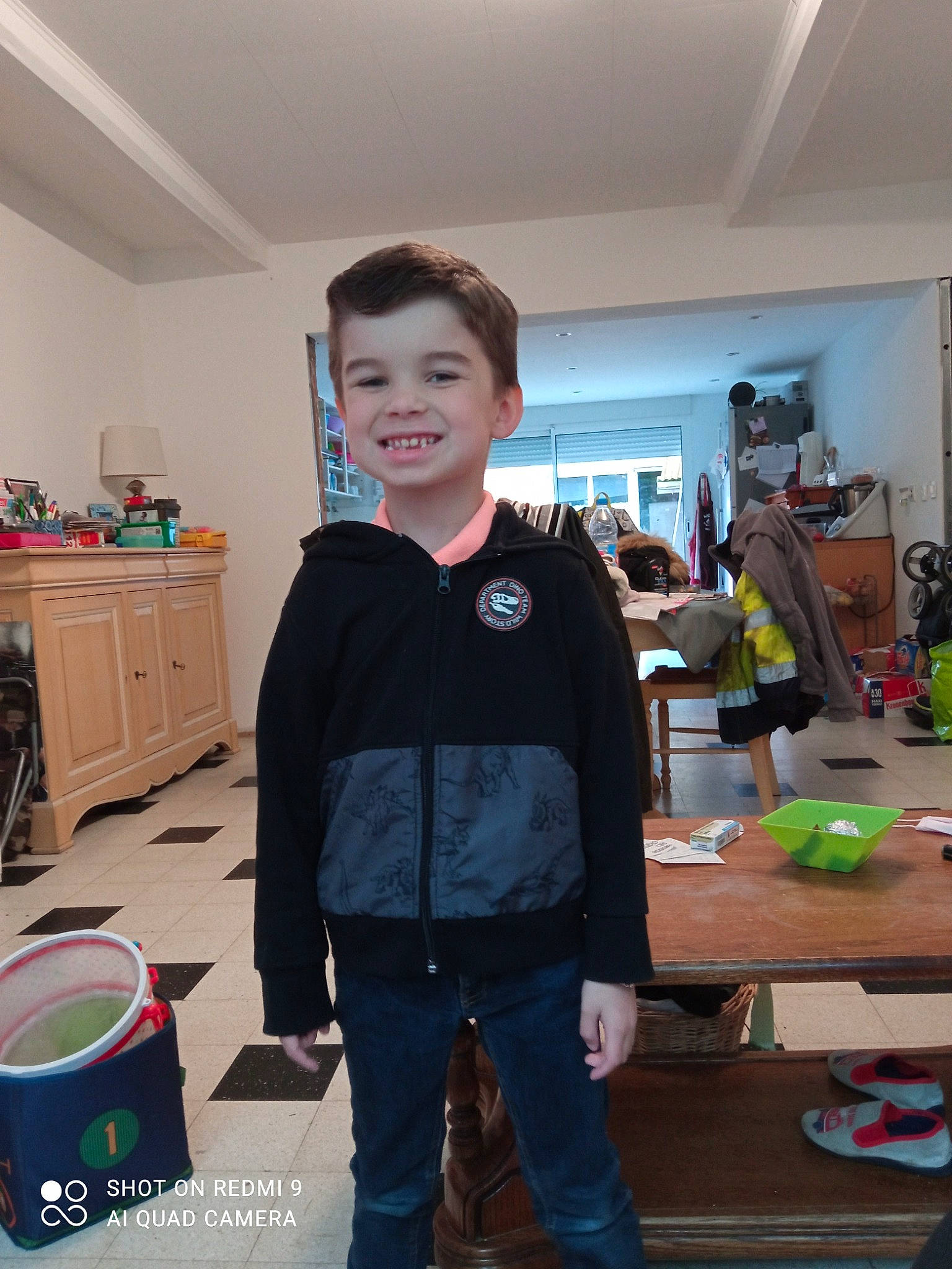 Léo participe au concours pour gagner de l'argent avec cette photo : cabinetry, chair, child, clothing, denim, desk, drawer, electric_blue, event, flooring, fun, joy, person, play, room, sleeve, smile, standing, t_shirt, table