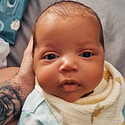 Tavontae is registered to the contest to win money with this photo: baby, infant, face, close_up, hand, tattoo, bib, clothing, blue, expression, eyes, skin, newborn, cute, portrait, person, soft, indoor, cozy, child