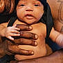 baby, infant, child, adult, hands, tattoo, headwear, black_head_covering, skin, close_up, portrait, indoor, caring, love, family, expression, looking_at_camera, holding, bare_chest, diaper