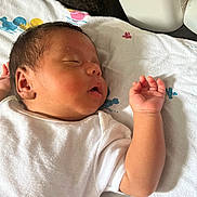 Adeline is registered to the contest to win money with this photo: baby, sleeping, infant, white_onesie, hand, towel, face, peaceful, closed_eyes, skin, newborn, resting, indoors, soft_light, cute, child, portrait, human, lying_down, small