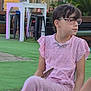 Lou participe au concours pour gagner de l'argent avec cette photo : child, girl, pink_dress, glasses, outdoor, green_turf, sitting, table, stools, plants, chain_necklace, short_hair, earrings, casual, daylight, people_in_background, furniture, relaxed, summer, portrait