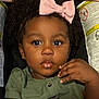 toddler, child, face, curly_hair, pink_bow, green_shirt, car_seat, eyes, hand, food_stain, portrait, indoor, cute, baby, skin, expression, person, clothing, earrings, closeup