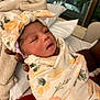 baby, bed, blanket, cozy, cute, family, floral, hand, headband, indoor, infant, newborn, person, pillow, portrait, resting, sleepy, soft, swaddled, warm