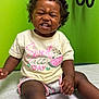 Samani is registered to the contest to win money with this photo: toddler, child, curly_hair, pink_bow, yellow_shirt, watermelon_graphic, scrunched_face, sitting, medical_table, green_wall, shorts, playful_expression, indoor, cute, person, young_child, skin, clothing, portrait, baby