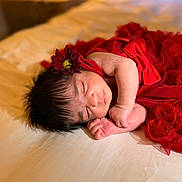 Gia joined the competition — help win amazing prizes! baby, newborn, sleeping, red_dress, flower_headband, bed, soft_lighting, peaceful, infant, portrait, indoors, cozy, cute, child, resting, tender, closeup, human, skin, face
