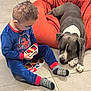 Magnum participe au concours pour gagner de l'argent avec cette photo : bean_bag, blue_clothing, boy, casual, child, companionship, dog, floor, glasses, gray_dog, home, indoor, pajamas, pet, playing, relaxed, socks, tile, uno_cards, white_markings