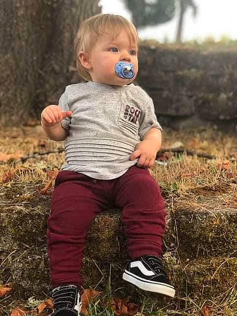 Finley is registered to the contest to win money with this photo: baby, baby_toddler_clothing, face, finger, footwear, grass, happy, head, leg, nature, people_in_nature, person, plant, shoe, smile, sneakers, sunlight, t_shirt, toddler, tree