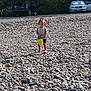 car, child, daylight, girl, gravel, nature, open_car_door, outdoor, play, recreation, rocks, shoes, shorts, sleeveless_shirt, standing, summer, sunlight, trees, vehicle, yellow_bucket