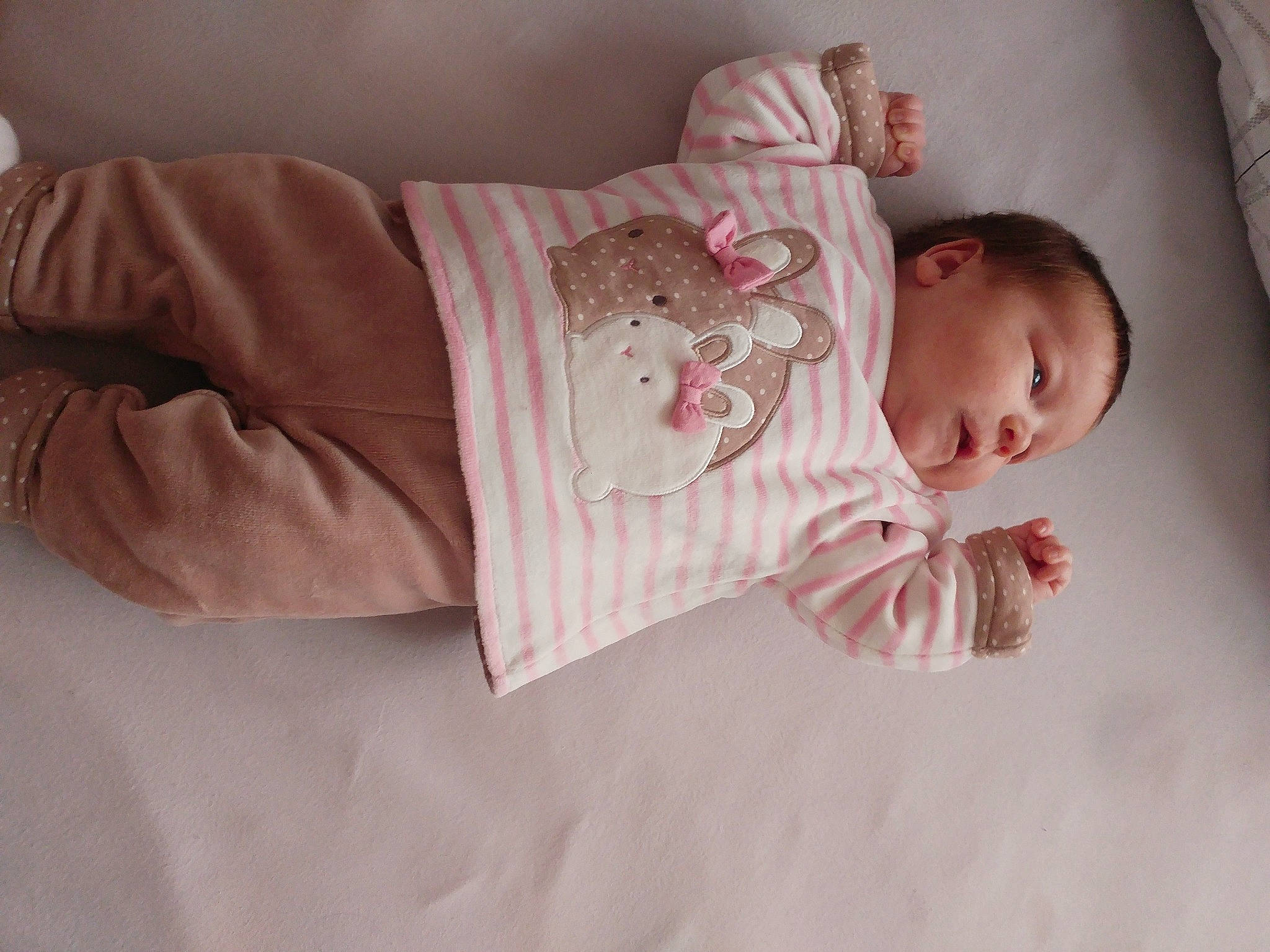 Lhéna participe au concours pour gagner de l'argent avec cette photo : arm, baby, baby_products, baby_toddler_clothing, cheek, comfort, dress, eye, face, hand, head, headgear, human_body, iris, lip, person, pink, skin, sleeve, textile