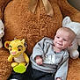 baby, teddy_bear, plush_toy, smiling, gray_sweatshirt, black_pants, white_shoes, stuffed_animal, lion_toy, white_bear_toy, sitting, indoors, cute, child, soft_toys, cozy, happy, infant, casual_clothing, comfort