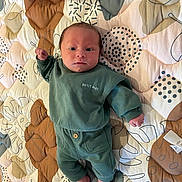 Loé a rejoint le concours — aidez-le/la à gagner de superbes lots ! baby, infant, child, green_clothing, sweatshirt, pants, barefoot, quilt, patterned_bedspread, lying_down, indoor, portrait, cute, small_hands, small_feet, expression, face, head, newborn, sleepwear