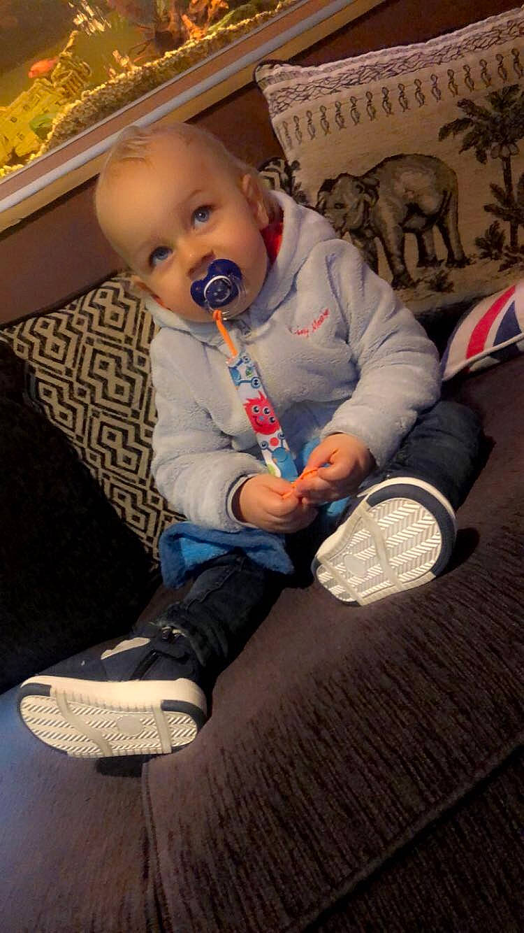 Mayron a rejoint le concours — aidez-le/la à gagner de superbes lots ! baby, baby_toddler_clothing, cheek, child, comfort, couch, eye, finger, flooring, fun, human_body, human_leg, lap, leg, person, shoe, sitting, sneakers, sock, toddler