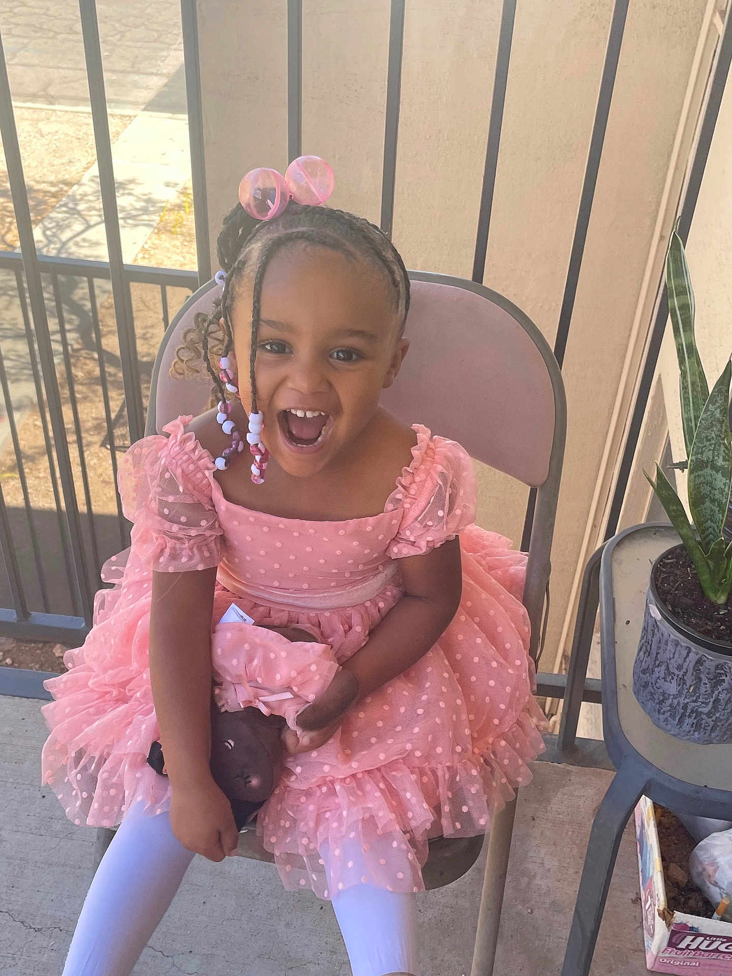 Levina joined the competition — help win amazing prizes! child, girl, pink_dress, braided_hair, beads, doll, chair, smiling, happy, outdoor, balcony, plant, pot, railing, white_tights, concrete_floor, sunlight, portrait, cute, joyful