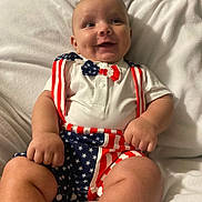 Makaius is registered to the contest to win money with this photo: baby, smiling, infant, patriotic, stars_and_stripes, bow_tie, suspenders, white_shirt, shorts, soft_blanket, chubby_arms, happy, cute, portrait, indoor, child, clothing, fashion, celebration, person