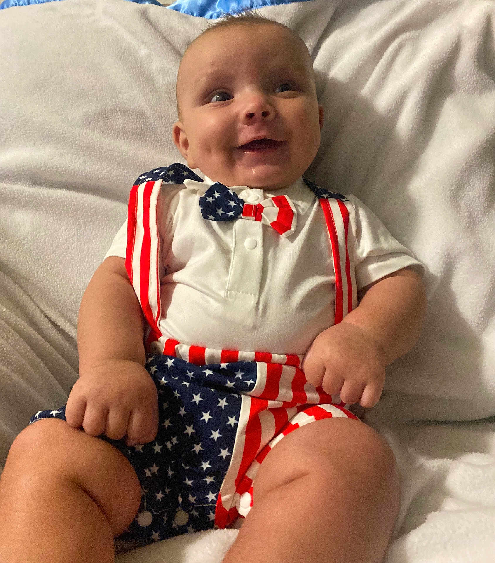 Makaius is registered to the contest to win money with this photo: baby, smiling, infant, patriotic, stars_and_stripes, bow_tie, suspenders, white_shirt, shorts, soft_blanket, chubby_arms, happy, cute, portrait, indoor, child, clothing, fashion, celebration, person