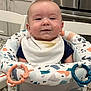 baby, bib, baby_walker, food_stain, smile, face, child, indoor, kitchen, high_chair, toy_rings, happy, clothing, person, infant, feeding, cute, seat, furniture, baby_toys