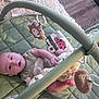 baby, infant, play_mat, baby_gym, plush_toys, green, indoor, floor, wooden_floor, curious, lying_down, child, cute, soft_toys, rings, clothing, head, face, person, carpet