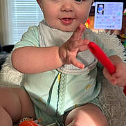 Cooper is registered to the contest to win money with this photo: baby, infant, child, smiling, hand, toy, blanket, indoor, curtains, window, television, couch, clothing, bib, face, legs, skin, furniture, play, happy