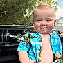 baby, child, smile, blue_shirt, hawaiian_shirt, short_sleeve, outdoor, tree, car, vehicle, person, cute, face, hair, hand, skin, daylight, happy, portrait, holding